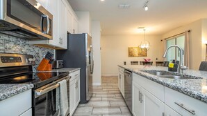 A modern kitchen with stainless steel appliances, granite countertops, and a central island. - Storey Lake 4 BR With Private Pool (Kissimmee)