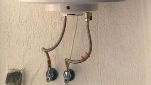 Um aquecedor Bosch fixado numa parede, com dois tubos visíveis ligados a ele.