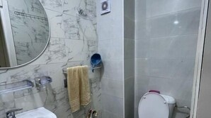 Um banheiro com pia, espelho, vaso sanitário e um balde verde no chão.