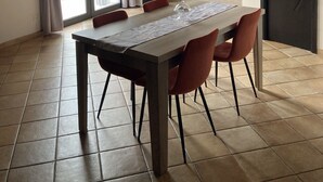 Ein Essbereich mit einem langen Tisch, Stühlen, einem Fernseher und einer Couch.