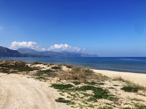 A beach with sand and sparse vegetation, a clear blue sky, and distant mountains. - "BEDDA MIA" Vacation Home   (Alcamo)