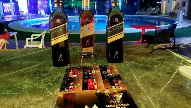 Three bottles of Double Black whiskey on a table with a promotional display. - Hotel Embassy Suites (Nauta)