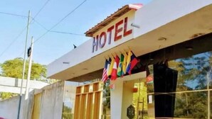 A hotel with a modern facade, a signboard displaying the word "HOTEL," and a variety of national flags hanging outside. - Hotel Embassy Suites (Nauta)