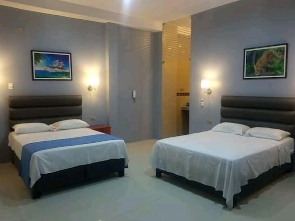 Two single beds with white linens, a nightstand, and wall-mounted lights. - Hotel Embassy Suites (Nauta)