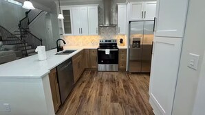 A modern kitchen with white cabinets, stainless steel appliances, and a wooden floor. - Cozy Jersey (Haw River)