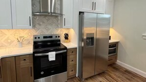 A modern kitchen with stainless steel appliances, wooden cabinets, and a herringbone-patterned backsplash. - Cozy Jersey (Haw River)