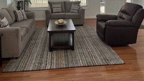 A spacious living room with a large window, a sofa, a chair, and a coffee table.