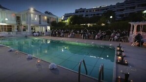 A swimming pool with a tiled deck, surrounded by a building with multiple windows and a balcony. - Rais El Marsa (Algiers)