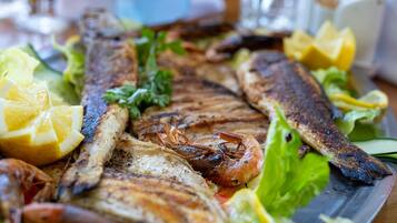 Una bandeja de mariscos con pescado a la parrilla, camarones y rodajas de limón.