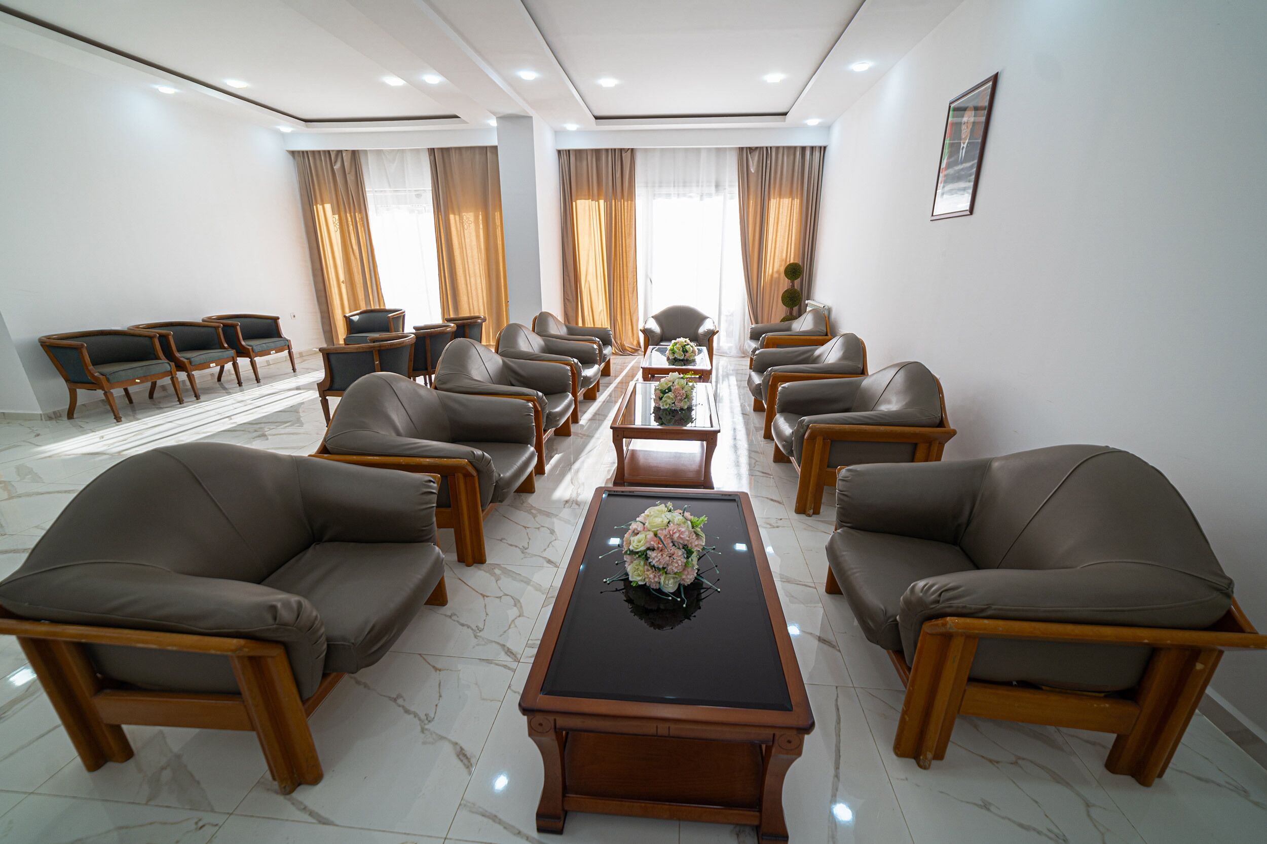 A hotel conference room with a long table, multiple chairs, and a floral centerpiece.