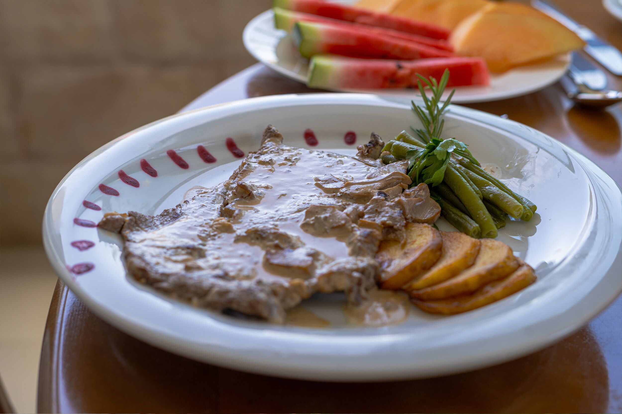 Un plato de comida con carne y verduras, una guarnición de pan en rodajas y hierbas frescas.