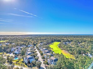 A residential area with a golf course, houses, and a clear sky.
