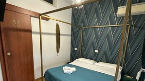 A room with a bed, a wardrobe, a hanging light fixture, and a wall-mounted air conditioner. - B&B Smeralda (Villa San Giovanni)