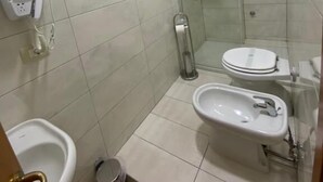 A small, tiled bathroom with a toilet, bidet, and a hand dryer. - B&B Smeralda (Villa San Giovanni)