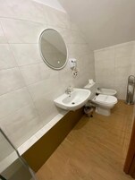 A bathroom with a sink, bidet, toilet, and a mirror.