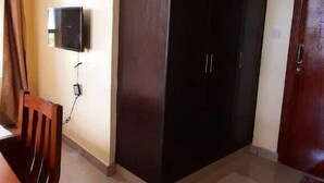 A room with a dark wardrobe, a wooden dining table, and a TV mounted on the wall. - Waiyaki way Heights (Mombasa)