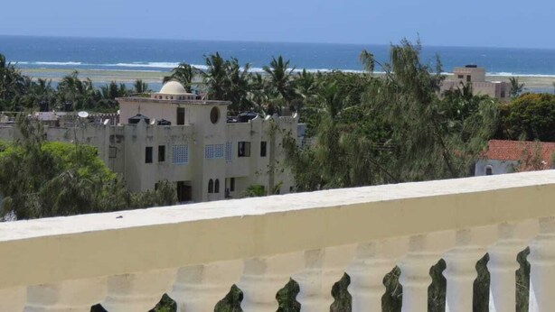 A coastal view with buildings, palm trees, and a clear sky. - Waiyaki way Heights (Mombasa)