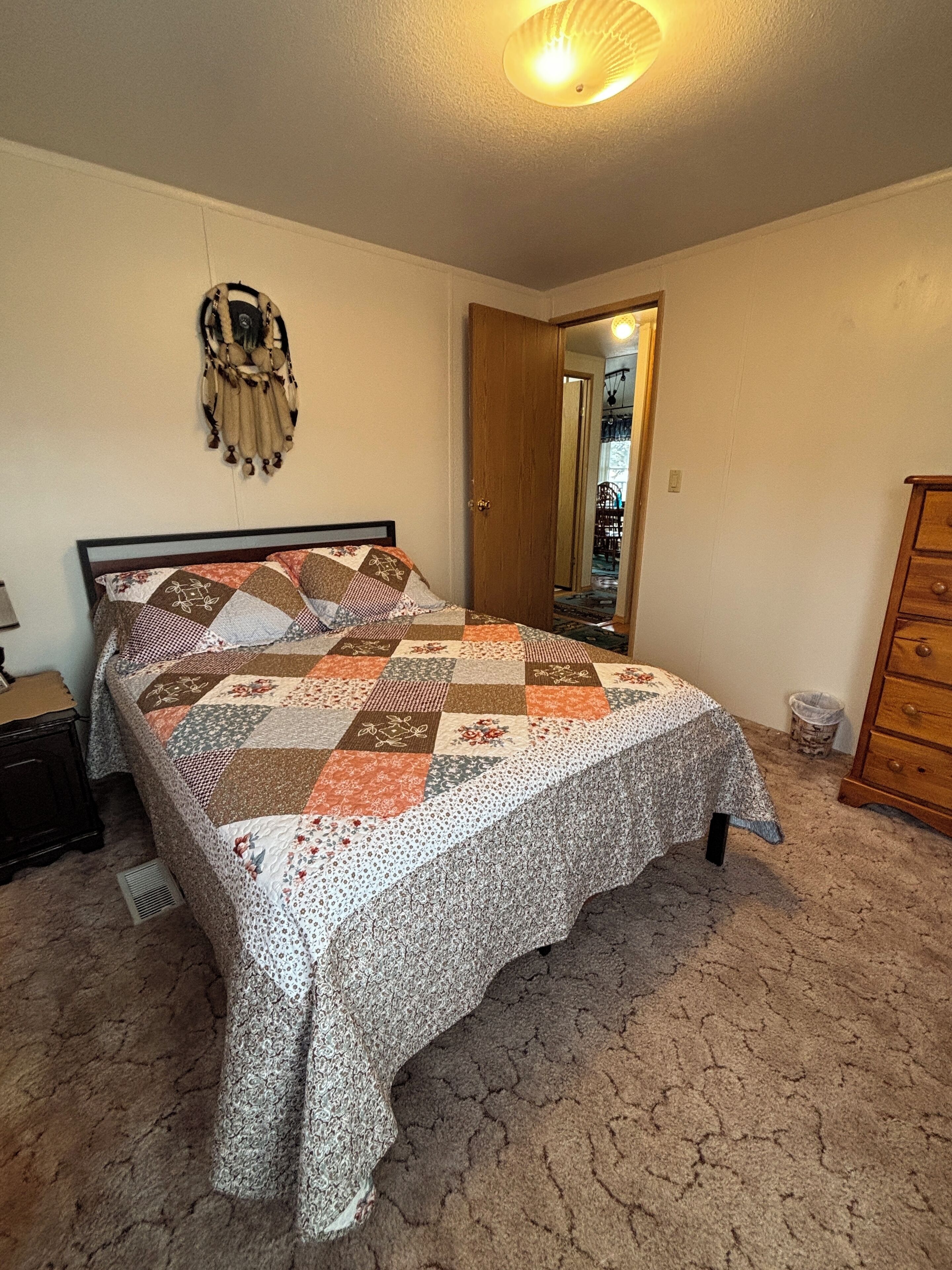Une chambre à coucher comprenant un lit, une commode, une table de chevet, un miroir et un élément décoratif mural.