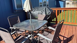 Une terrasse avec une table et des chaises, un barbecue et une plateforme en bois.