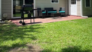Une maison avec un patio, du mobilier d’extérieur et un barbecue.