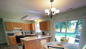 Une cuisine moderne avec des meubles en bois, un îlot central et un coin repas comprenant une table ronde et des chaises.