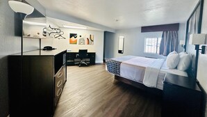 Una habitación de hotel con cama, escritorio, silla y un espejo grande.