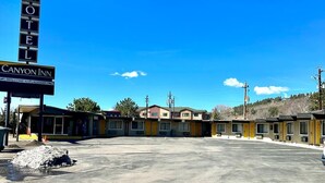 Un motel con un letrero llamativo que dice 'Motel', un letrero que dice 'Canyon Inn' y un mensaje de bienvenida. El edificio tiene un diseño sencillo y funcional, con varias habitaciones visibles.