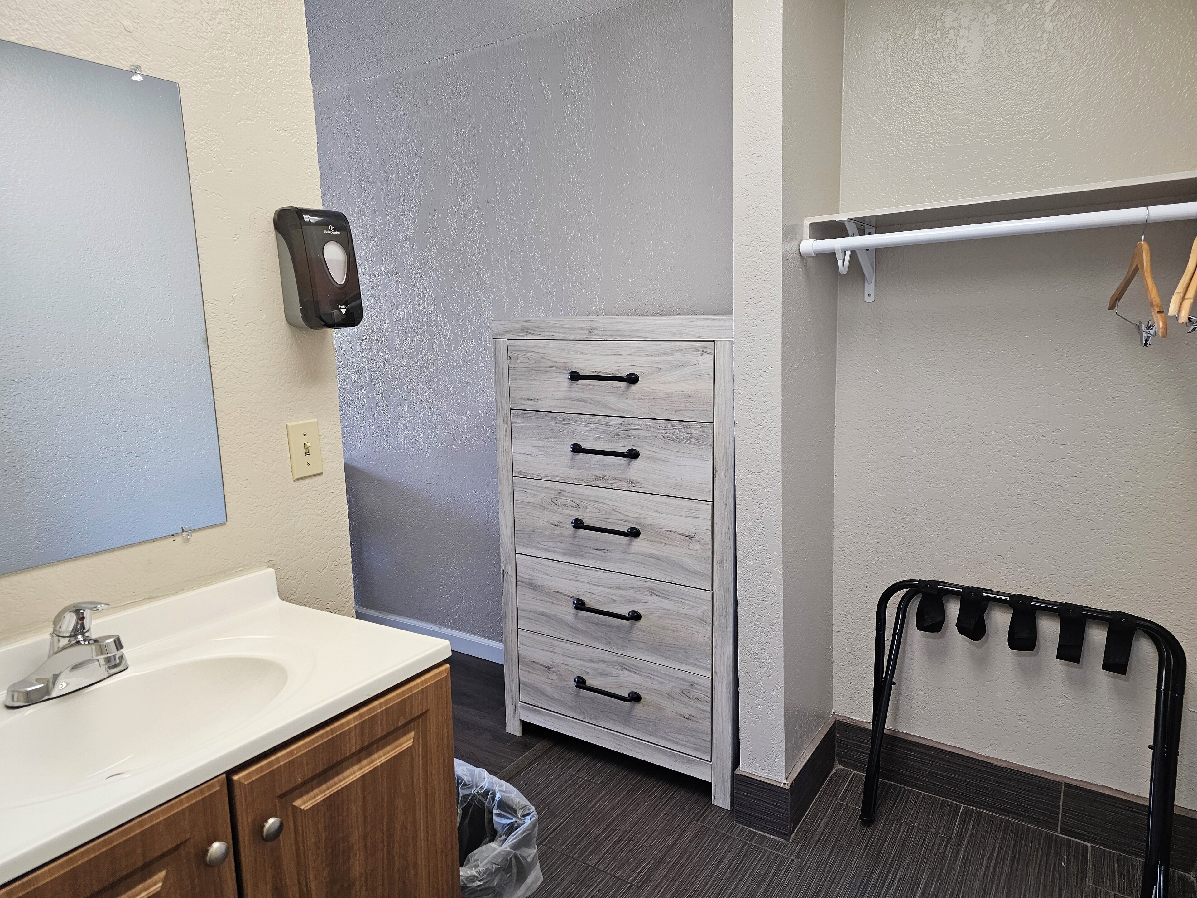 Un baño con un lavabo blanco, un mueble de madera y un almacenaje blanco con cajones.