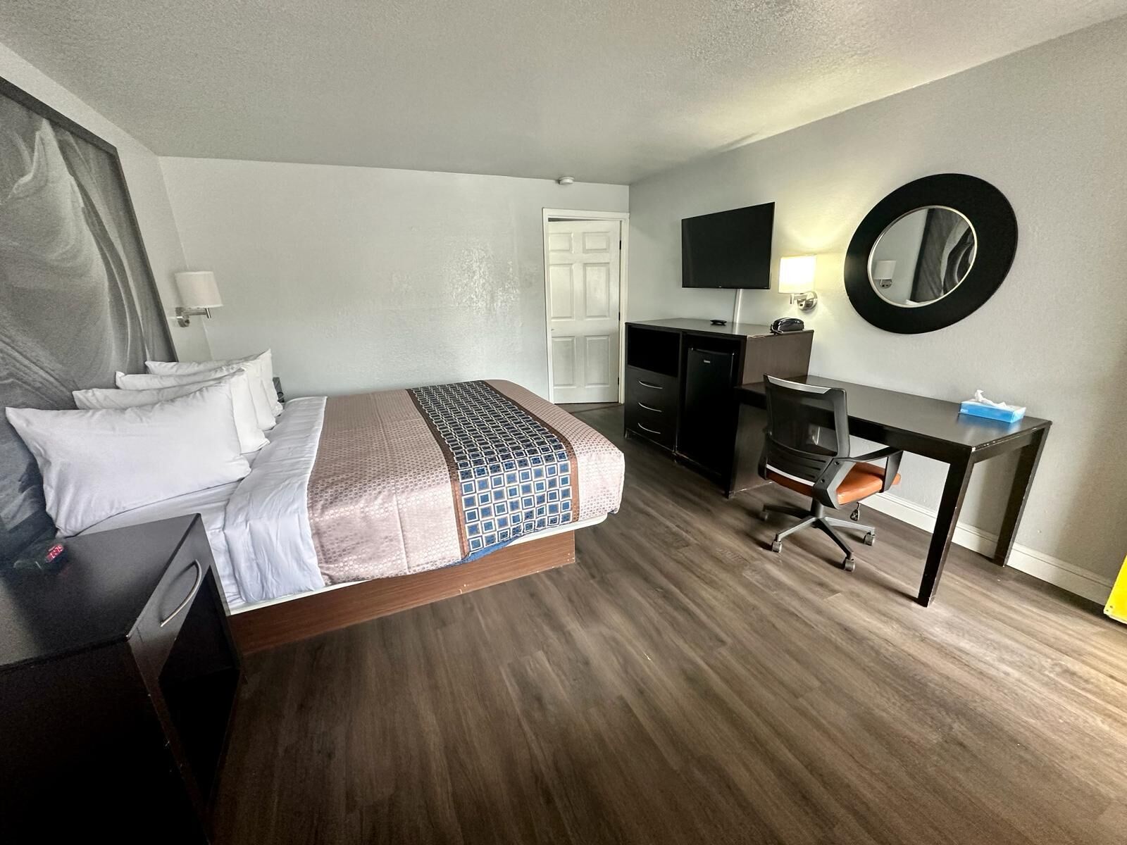 Une chambre d’hôtel équipée d’un lit, d’un bureau, d’une chaise, d’une télévision et d’un miroir.