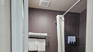Un baño con inodoro, bañera, cortina de ducha y toallero.