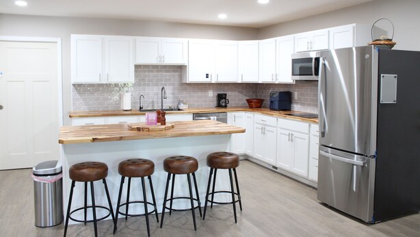 A modern kitchen with white cabinets, a stainless steel refrigerator, a wooden countertop, and four stools. - Luxury 2-bedroom apartment in excellent Manlius with WiFi, AC (Manlius)