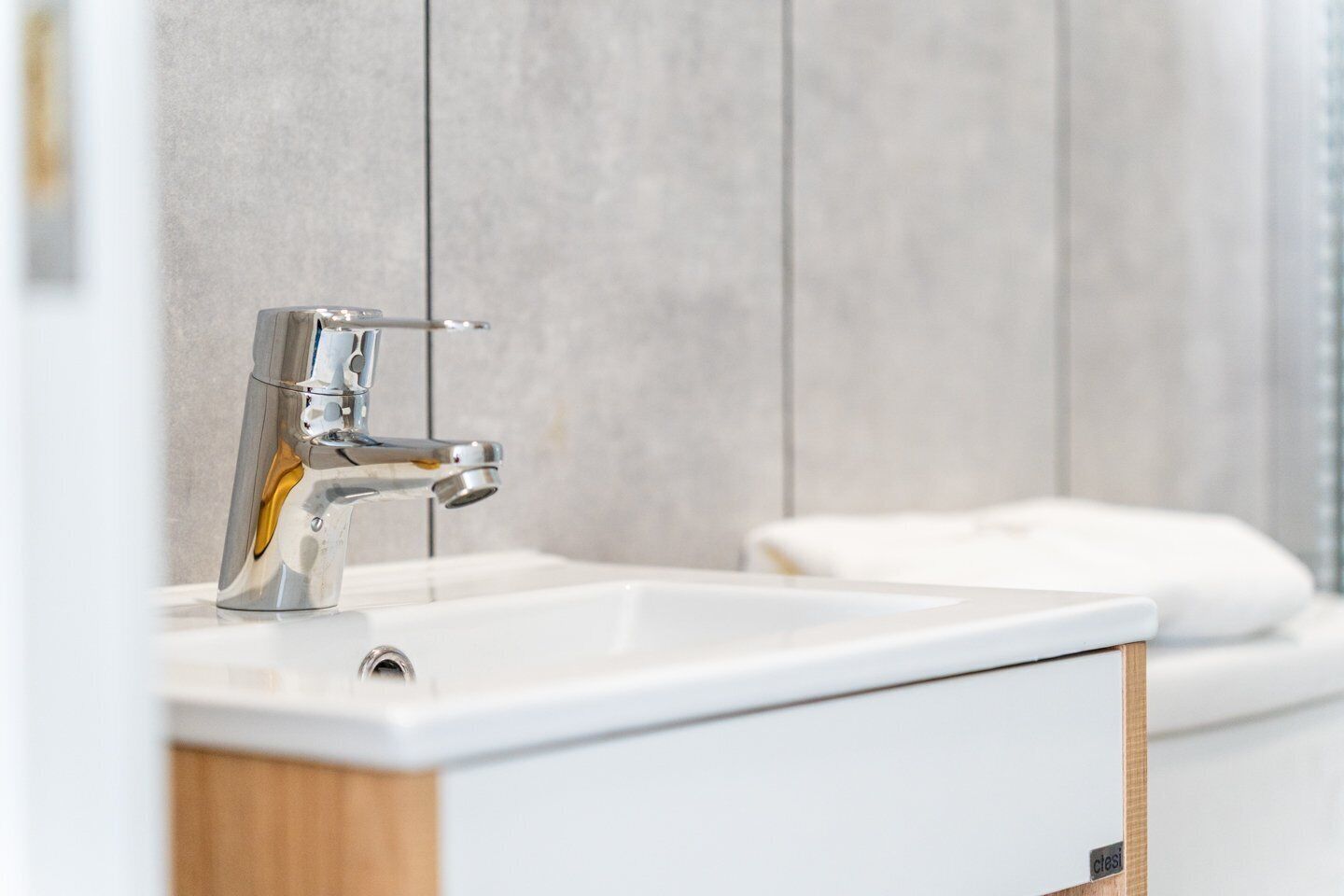 Une salle de bain moderne avec un robinet chromé, un lavabo blanc et un meuble en bois.