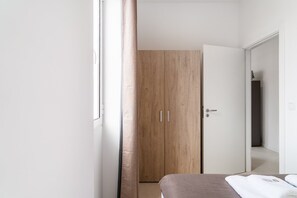 Une chambre à coucher avec un lit, une armoire en bois et une porte blanche.