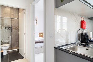 Une salle de bain moderne avec douche et toilettes, et une chambre adjacente.