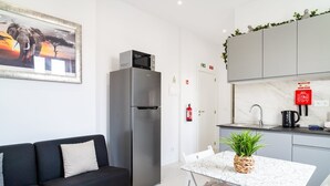 A compact living space with a kitchenette, a sofa, a dining table, and a framed picture of an elephant.
