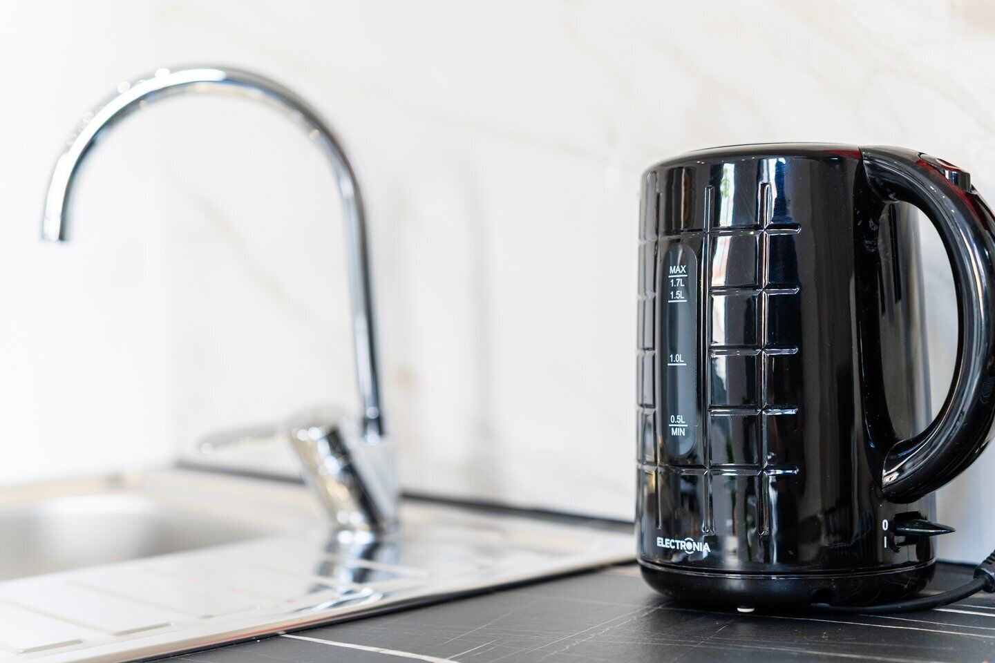 Une cuisine dotée d’un robinet moderne et d’une cafetière noire munie d’indications de dosage.
