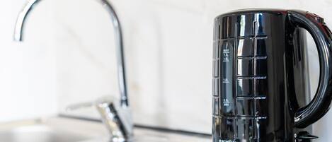 Une cuisine dotée d’un robinet moderne et d’une cafetière noire munie d’indications de dosage.