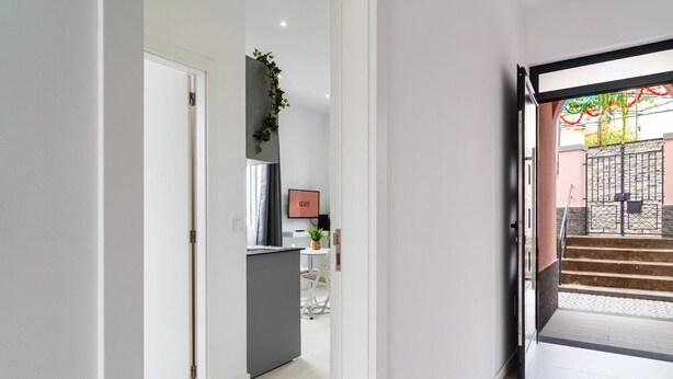 A hallway leading to a kitchen area with a modern design, a staircase, and a view of the outside.