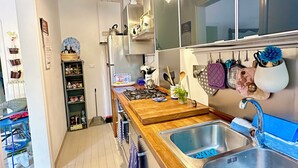 A modern kitchen with a wooden countertop, stainless steel sink, and hanging utensils.