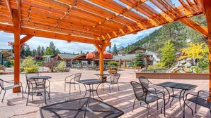 An outdoor patio with wooden pergola, tables, and chairs. - GroundFloor+Pool+King Bed+HotTub+Skiing (Leavenworth)