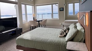 A bedroom with a bed, a TV, a desk, and a chair. - Cottage with East Suite at Sahhali on the Bluffs (Pender Island)