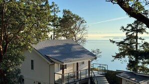A cabin with a balcony overlooking a lake, surrounded by trees. - Cottage w/ Vantage Suites at Sahhali on the Bluffs (Pender Island)