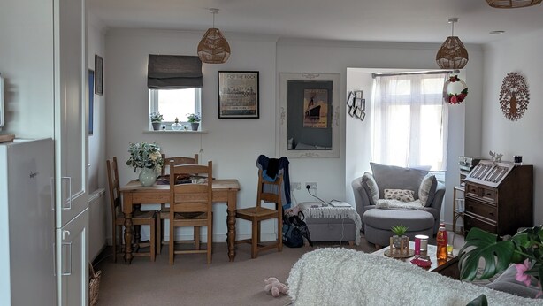 A living room with a grey sofa, a dining table with chairs, a small pet bed, a grey armchair, and a bookshelf. - Quite location near to the canal (Hythe)