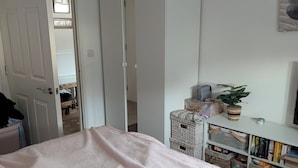 A bedroom with a bed, a wardrobe, a small table with a plant, and a bookshelf. - Quite location near to the canal (Hythe)