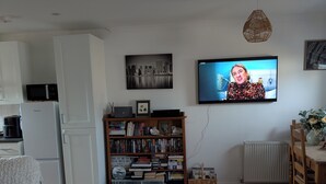 A living room with a sofa, coffee table, bookshelf, TV, and a dining area. - Quite location near to the canal (Hythe)
