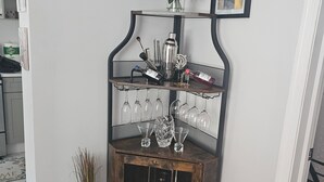 Eine gemütliche Bar mit Holzkabinent, Weingläsern und einem dekorativen Metallbild an der Wand.