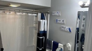 Un baño con bañera, inodoro y lavamanos. Hay toallas y una cortina de ducha.