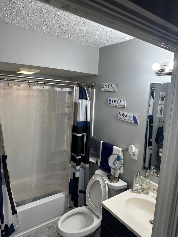 A bathroom with a bathtub, toilet, and sink. There are towels and a shower curtain.