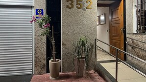 L’entrée d’un hôtel, avec un volet fermé, une enseigne portant le numéro 352 et deux plantes en pot.