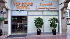 The exterior of the Top Stars Hotel with a modern design, featuring a large glass entrance and two potted plants in front. - Palette Top Stars Hotel (Abu Dhabi)